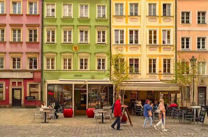 People stroll past vibrant building facades in Poland.