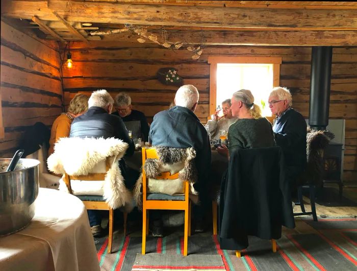 Guests enjoy lunch at a table set in a barn at Skølberg Søndre farm, Trøndelag, Norway