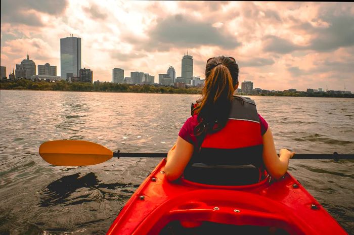 A teenager in a red kayak glides down a river.