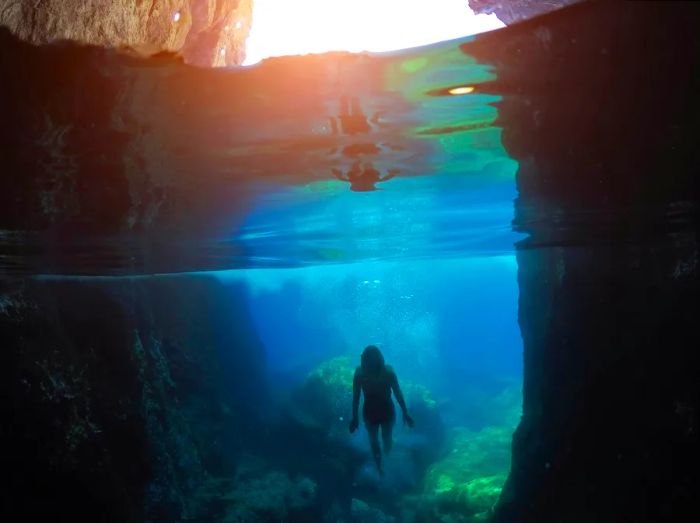 A woman gracefully swims underwater near a submerged cave in Florida