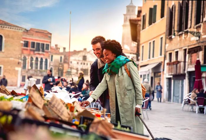 A couple in trench coats explores a stall filled with souvenirs on the streets.