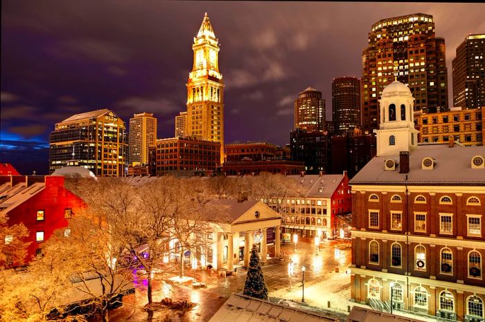 A light dusting of snow blankets bare tree branches in Faneuil Hall Marketplace, where festive lights and sparkling Christmas trees abound, as Boston embraces the holiday spirit.