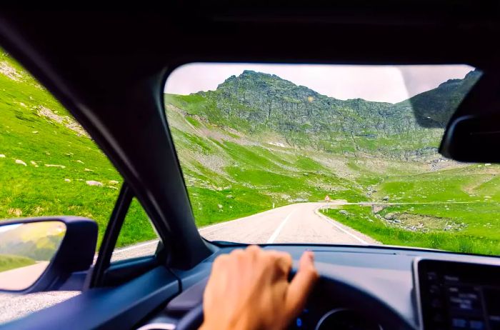 A driver navigating a mountain road in Romania