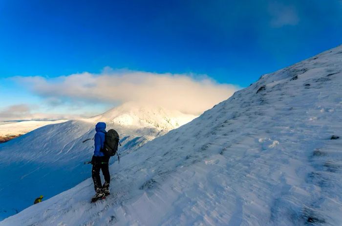 A hiker treks through the snow in the Highlands, Scotland, United Kingdom