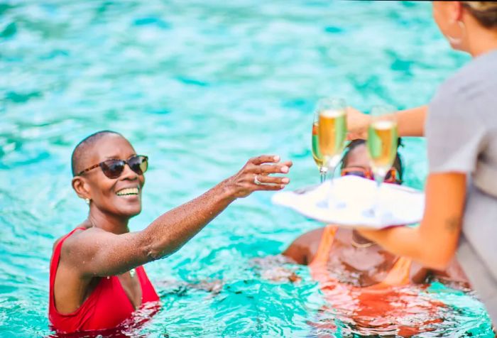 Serving glasses of champagne to her clients by the pool at a luxurious private villa.