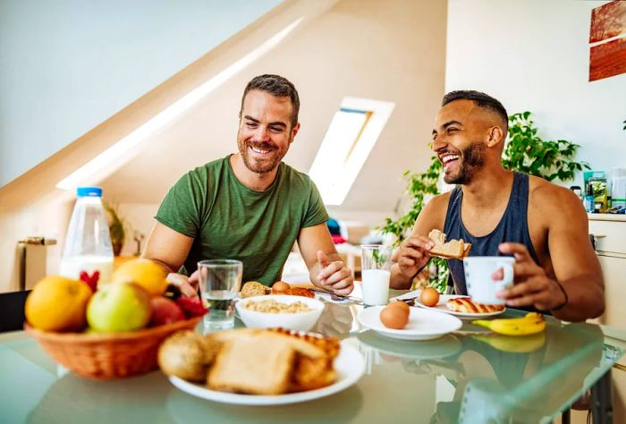 A gay couple enjoys a cheerful breakfast together at home, filled with laughter and appreciation for one another.