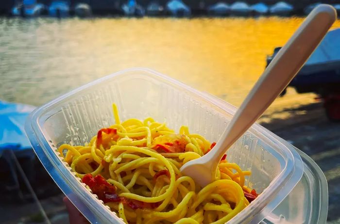 A takeout container filled with pasta enjoyed by the lakeside in Bellagio, Italy