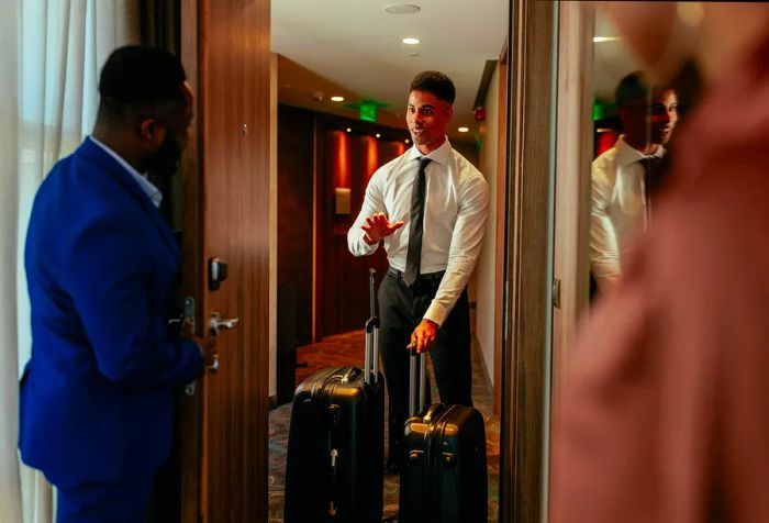 A young hotel staff member is delivering luggage to the VIP guests in the presidential suite.