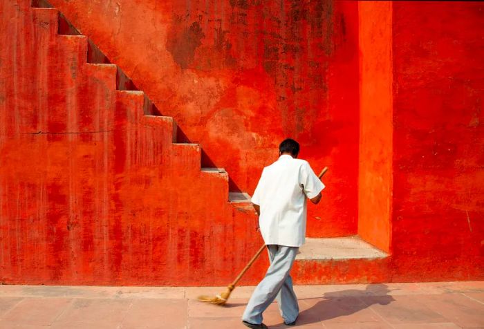 A man sweeping a paved street alongside the stairs.