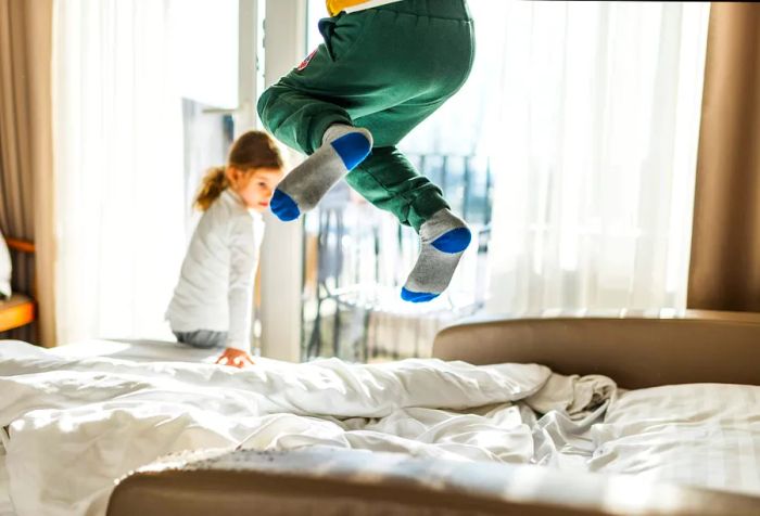 A young child in socks joyfully jumping on a bed.