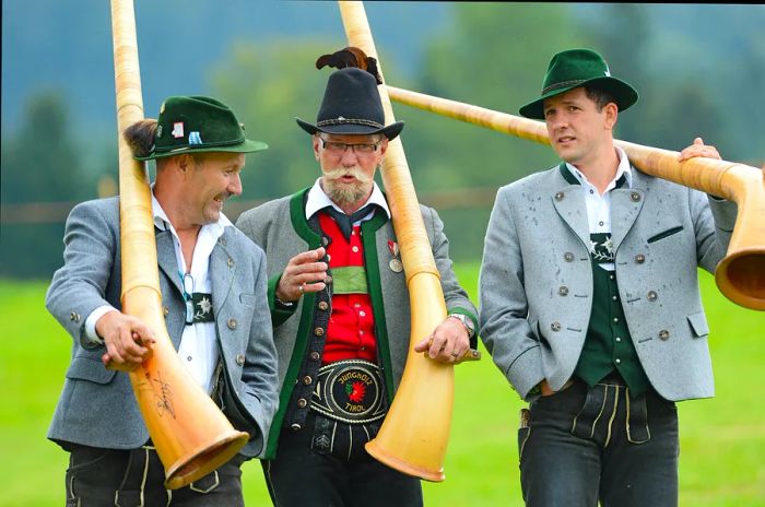 Three Alphorn players descend a hill after their performance at the Alphorn blowers gathering in Weiler-Simmerberg