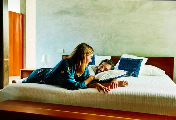 A young couple enjoying a conversation on the bed in a hotel room.