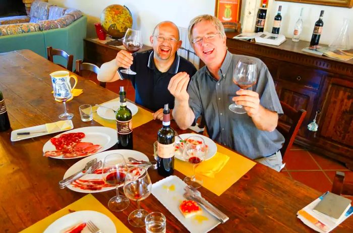 Rick Steves enjoying wine and charcuterie with a friend at a dining table