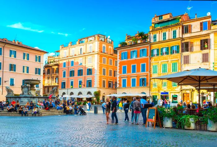 A lively public square where people relax on steps surrounding a fountain and wander past al fresco cafes.