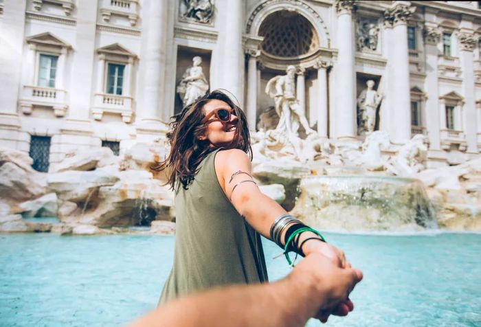 A woman wearing sunglasses smiles back while holding someone's hand.