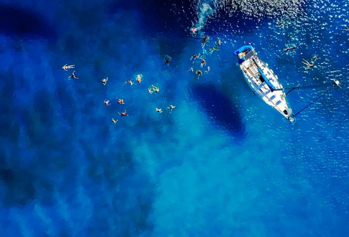 Aerial view of a group enjoying a swim in the azure waters beside a yacht ©Dusan Petkovic/Shutterstock