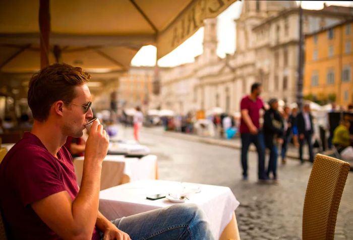 A man enjoys his espresso at an outdoor café.