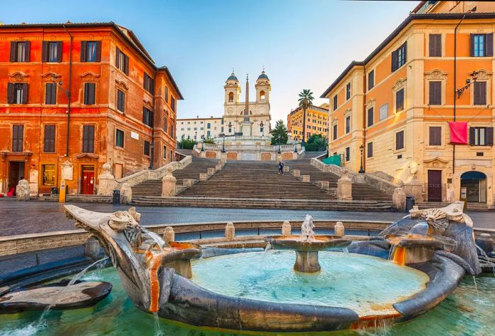 An ancient fountain stands in front of the Spanish Steps and the Trinità dei Monti.