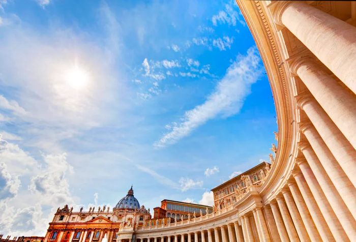 The elegant colonnade and the basilica in St. Peter's Square bathed in bright sunlight.