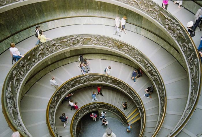 Visitors elegantly navigate a stunning spiral staircase within the Vatican Museum.