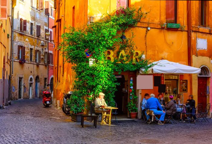 Locals gather at an outdoor bar next to a quaint street filled with traditional townhouses.