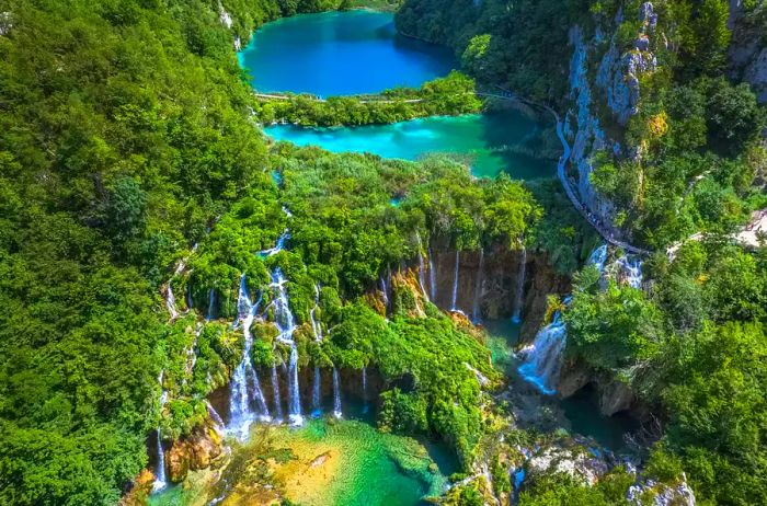 An aerial perspective showcases the stunning terraced lakes of Plitvice Lakes National Park, a UNESCO World Heritage Site located in central Croatia's mountainous karst region.