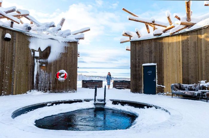 A stunning view of the Arctic Bath Hotel, featuring an ice plunge pool surrounded by various buildings during daylight.