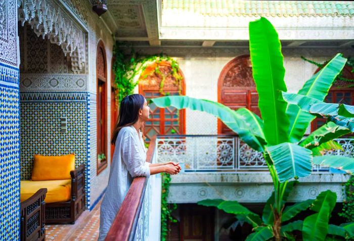 A female traveler lost in thought rests her arms on the balcony.