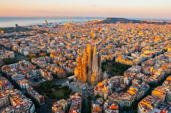 Aerial view of Barcelona's skyline featuring the Sagrada Familia Cathedral at dawn.