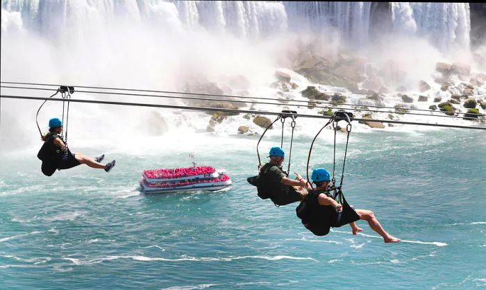 Riders clipped into a zip line soar over Niagara Falls, Ontario, Canada