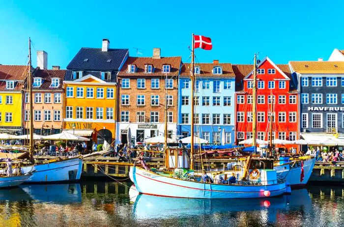 A panoramic view of Nyhavn, bustling with crowds basking in the sunshine and enjoying the vibrant restaurants along the waterfront in Copenhagen.