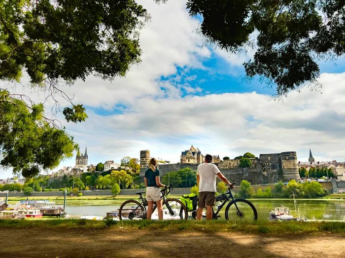 A female cyclist poses beside her bike in front of Angers in the Loire Valley, France.