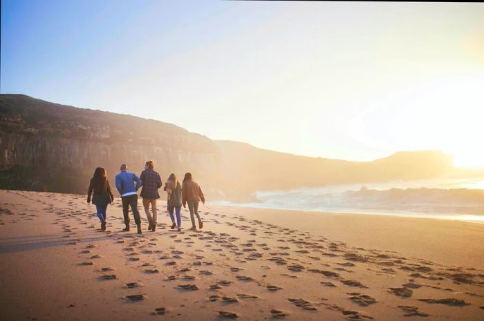 A group of friends enjoying a sunset stroll on the beach