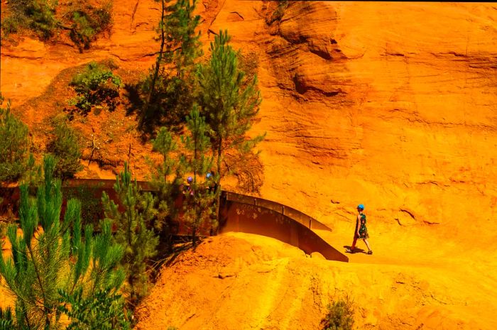 Hikers in a vibrant ochre landscape along the Sentiers des Ocres near Roussillon, France