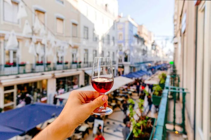 A person enjoying port wine on a street in Lisbon, viewed from a personal perspective, Lisbon, Portugal