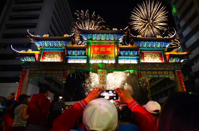 A man captures the moment on his mobile phone as fireworks light up the sky above the friendship arch in Chinatown, the largest in the world, located in the Binondo district of Manila, during Chinese New Year's Eve celebrations.