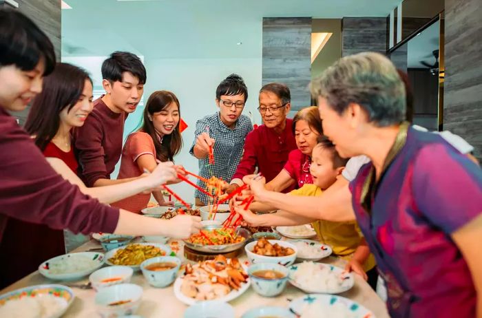 A family enjoying a reunion dinner on Lunar New Year's Eve, featuring the traditional raw fish salad, Lou Sang.