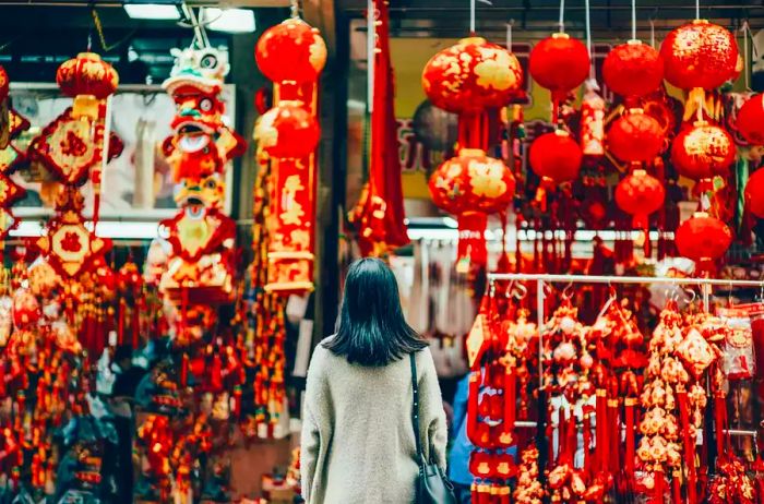 A woman seen from behind amidst vibrant Lunar New Year decorations on a city street