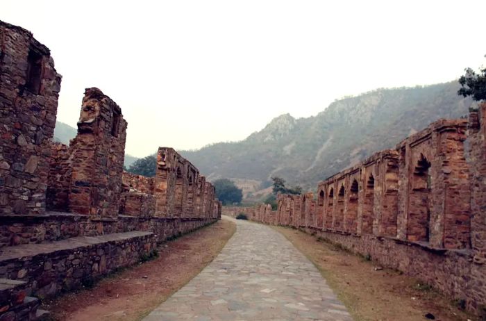 A path winding through ancient ruins on a hauntingly misty day