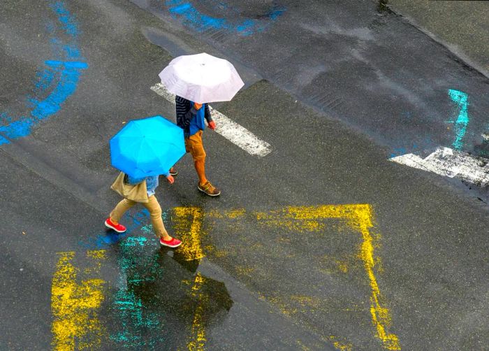 Aerial view of a rainy street with two people walking under umbrellas in Brussels