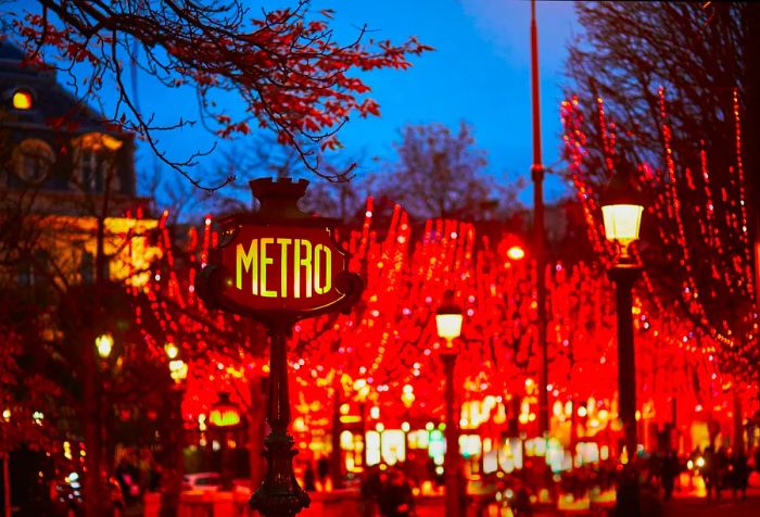 Subway station sign and seasonal holiday illuminations along Champs Élysées in Paris, France, celebrating Christmas and New Year in the French capital.