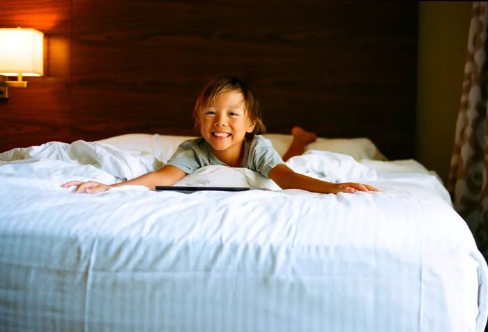 A young boy sprawled out on a large bed, enjoying his time.