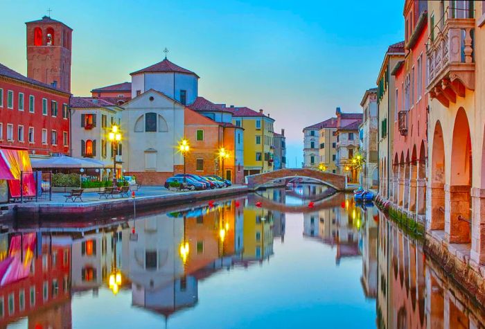 A view of Canal Vena at twilight in Chioggia, framed by vibrant buildings on both sides