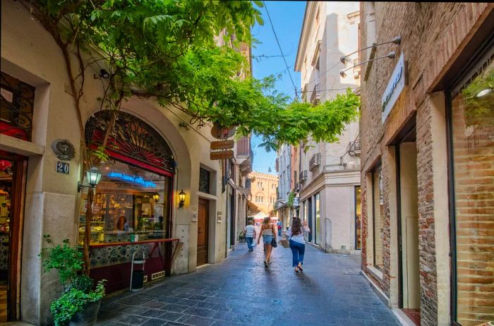 Pedestrians stroll along Barberia Street, close to Signori Square, in Treviso.