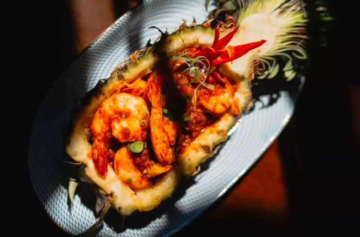 A dish featuring pineapple and prawns cast in shadow.