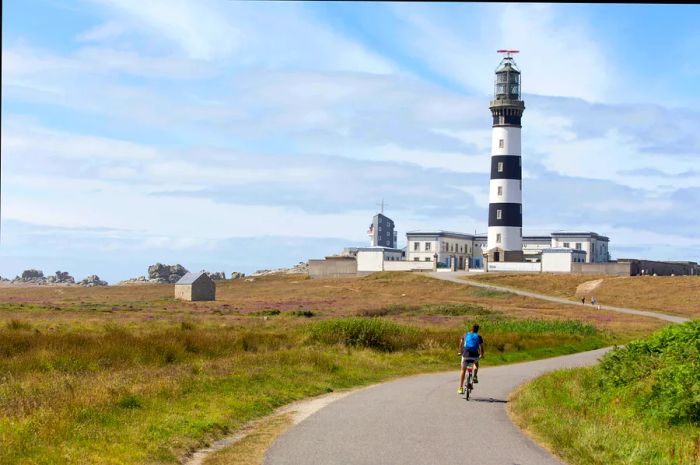 Person cycling past a lighthouse on Île d’Ouessant, France