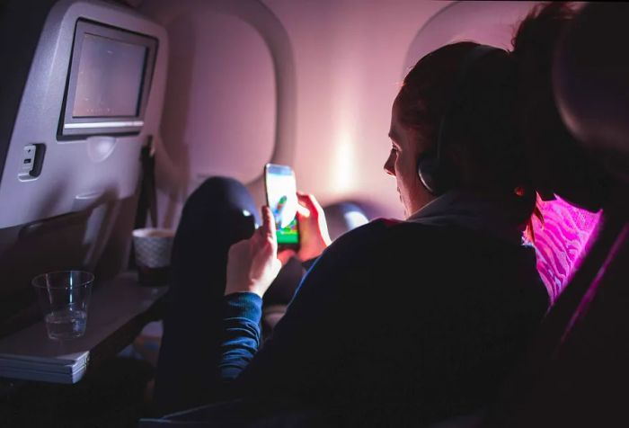 Woman Using a Mobile Phone While Relaxing on an Airplane.