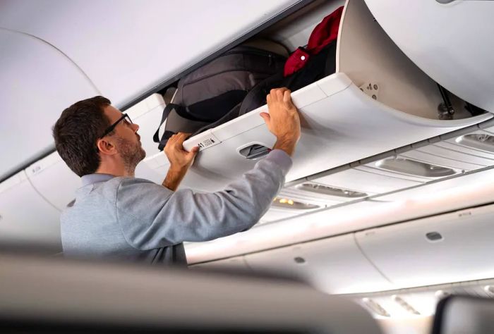 Man placing luggage into the overhead compartment.