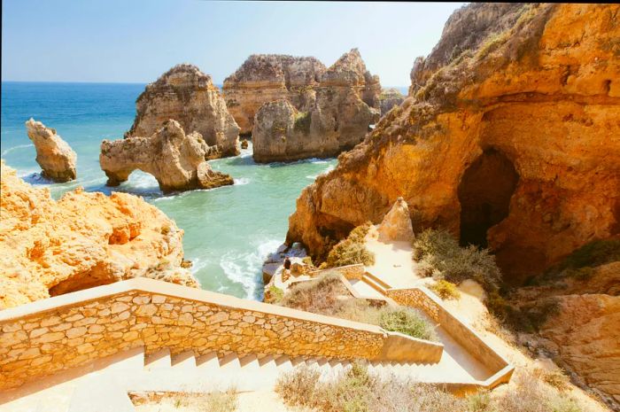 A rocky cliff seascape with steps leading to the beach in Lagos, Algarve, Portugal. Ponta Da Piedade Beach in Lagos.