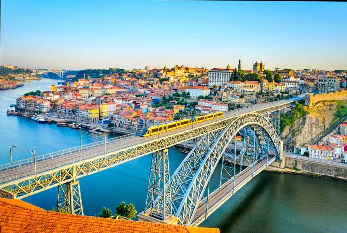 A metro train crosses the Dom Luis bridge, with the historic city of Porto in the background.